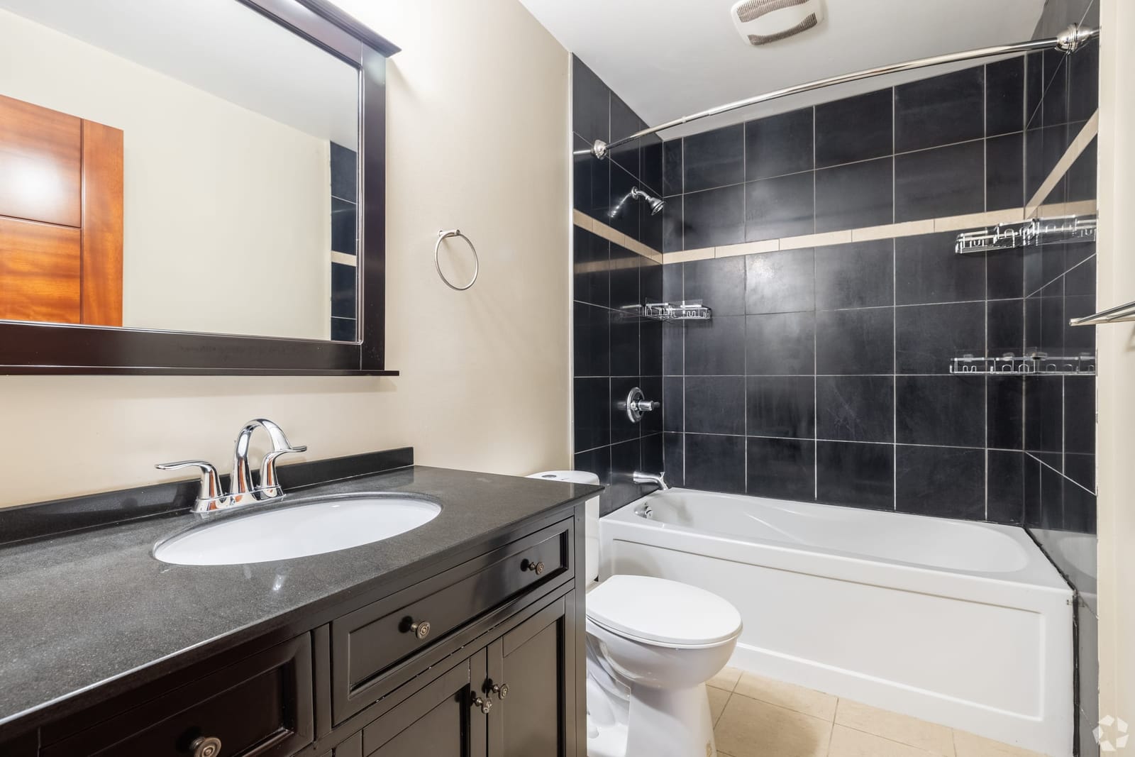 Bathroom with dark tile surround, soaker tub and granite vanity