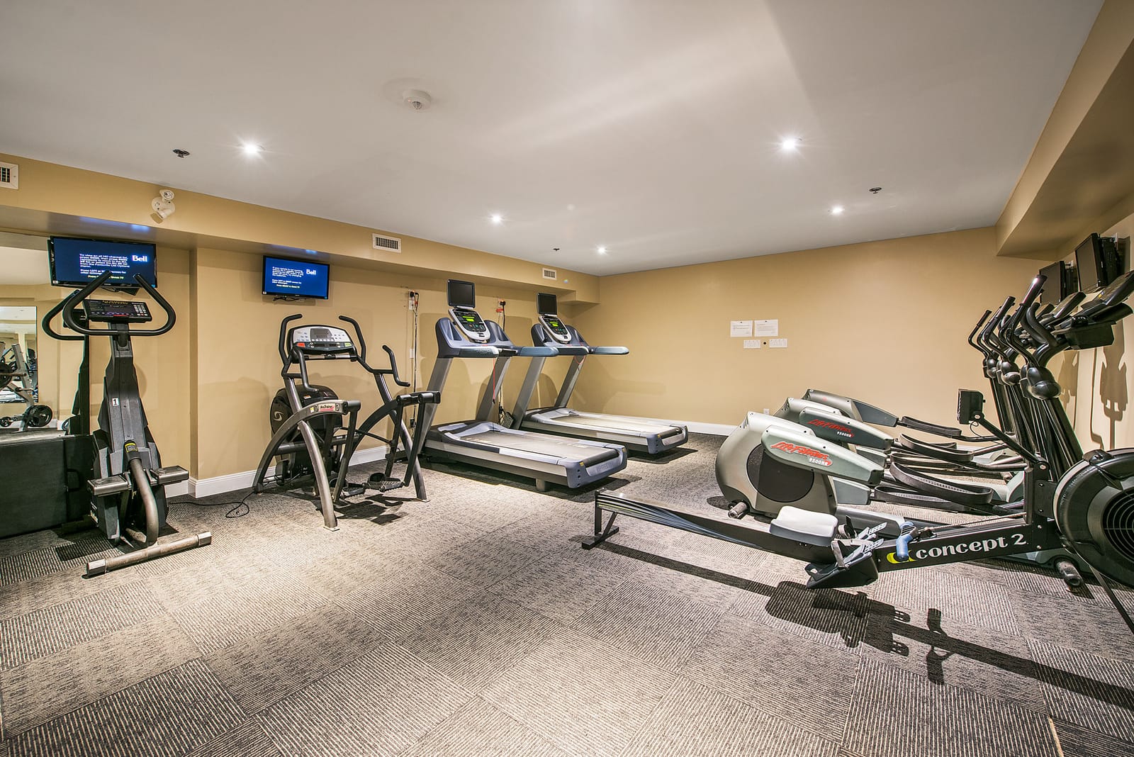 Fitness centre cardio row with treadmills, ellipticals, a bike and a rowing machine