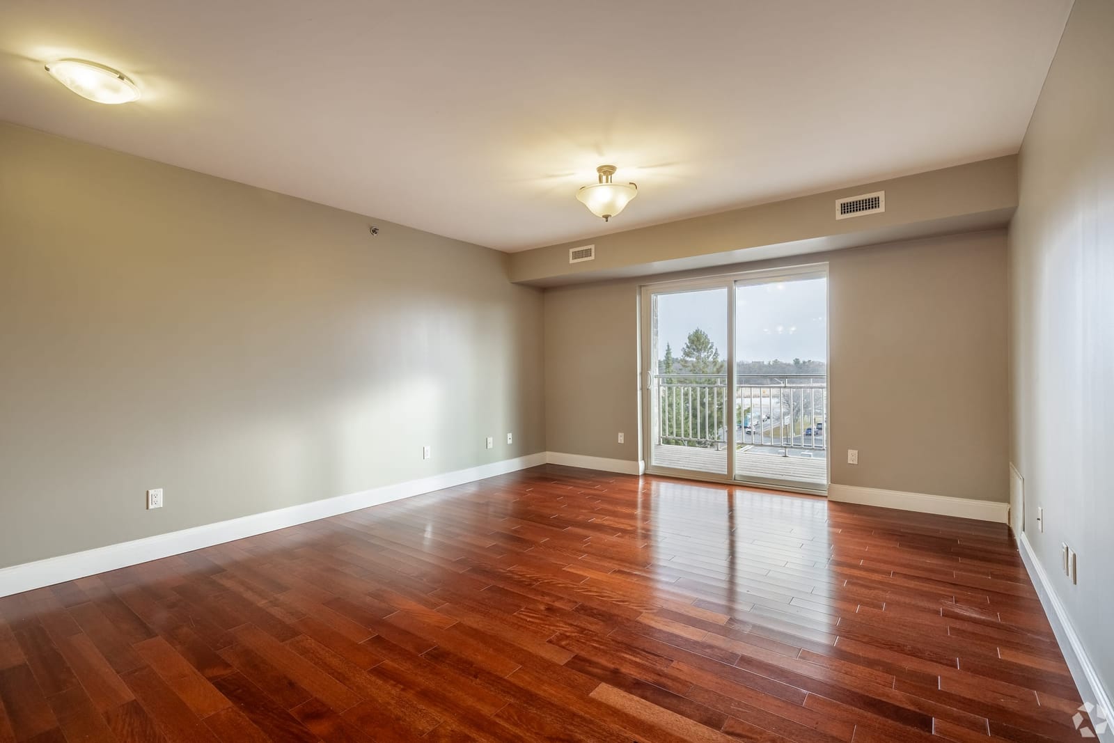 Living room with walnut hardwood floors and a walkout to the balcony
