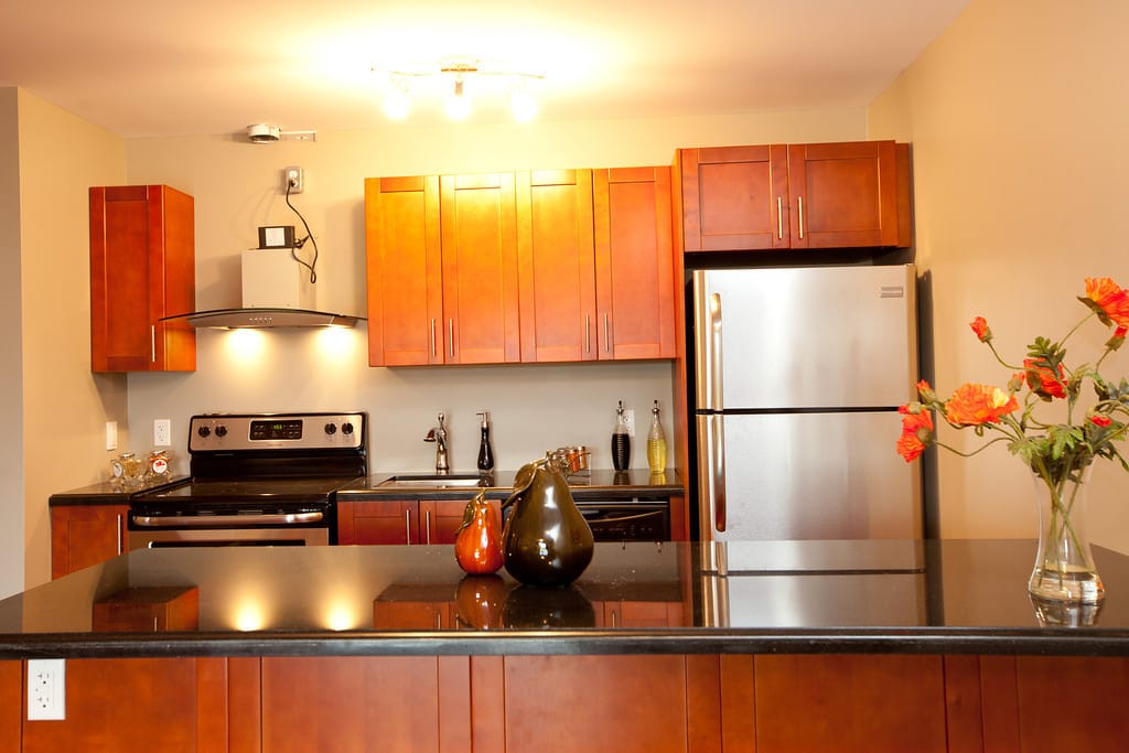 Suite kitchen with granite counters, cherry cabinetry and a stainless fridge